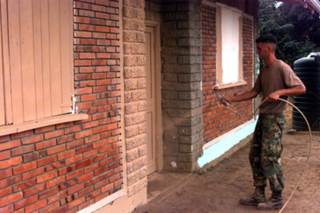 Lance Cpl. Kevin Grimstead uses a paint spray gun to put the finishing touches on the outside of the recreation center/dining facility for the military campsite at Kumaka, Guyana, on Aug. 12, 1997. The site is the temporary home for more than 50 military medical and engineer personnel working in support of the joint-combined humanitarian Exercise New Horizon Guyana 1997. U.S. forces, the Guyana Defense Force and local community leaders are working together to accomplish engineer construction and medical projects. Grimstead, of Wichita, Kan., is a combat engineer from Marine Wing Support Squadron 274, Cherry Point Naval Air Station, N.C. 
