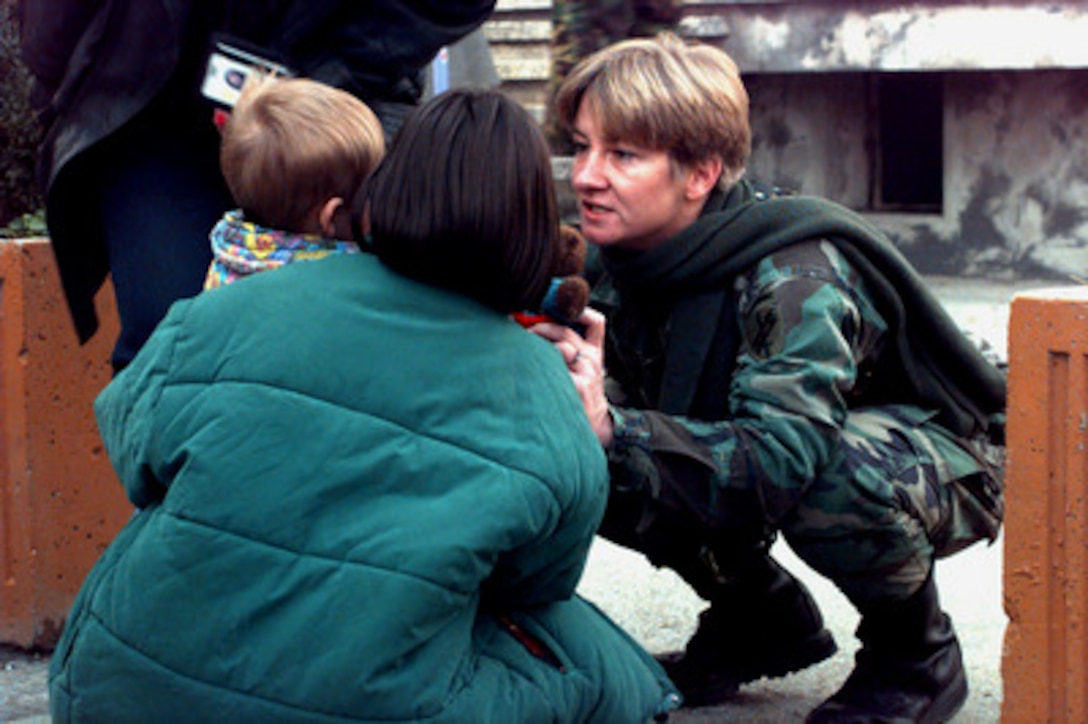 U.S. Army Reserve Capt. Lisa Woodbury gives a small child a stuffed animal at a shelter in Sarajevo, Bosnia and Herzegovina, on Nov. 5, 1997. Woodbury works at the Civil Military Campaign in Sarajevo in support of Operation Joint Guard. The toys and clothing she is distributing were donated by the people of the United Kingdom and gathered by the Royal Air Force unit based in Split, Bosnia and Herzegovina. Woodbury is attached to the 351st Civil Affairs Command, Mountain View, Calif. 