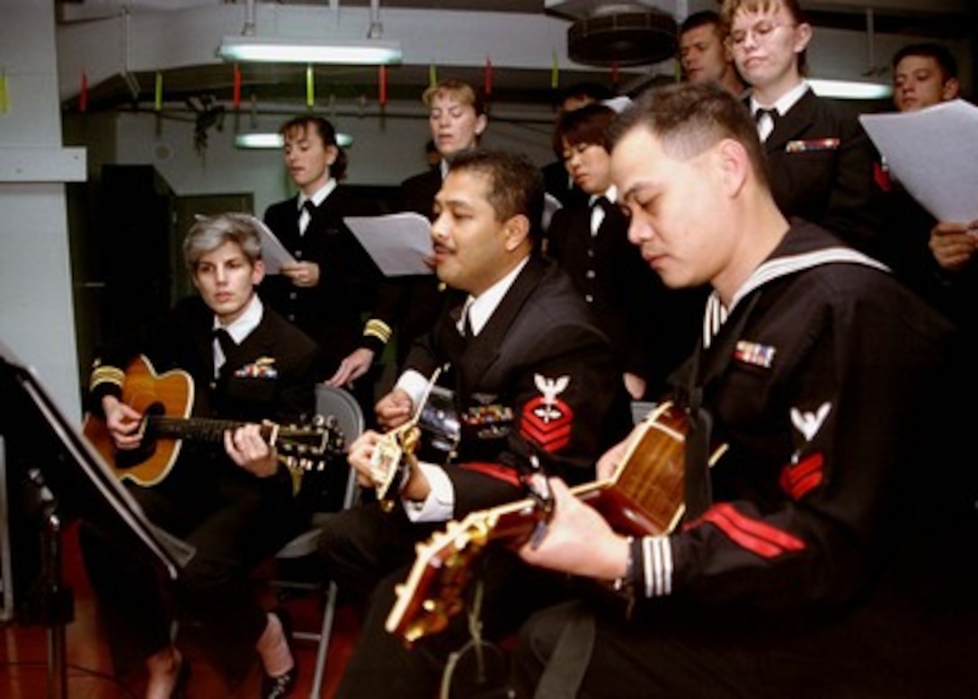 Petty Officer 2nd Class Feliciano Valencia (right) from Pampanga, Philippines, Chief Petty Officer Rene Abadesco (center) from Davao City, Philippines, and Lt. Cmdr. Donna Sengelaub (left) from Camp Springs, Md. provide musical accompaniment during the Roman Catholic midnight Mass aboard the aircraft carrier USS Nimitz (CVN 68) in the Persian Gulf on Dec. 25 1997. The Nimitz and embarked Carrier Air Wing 9 are operating in the Persian Gulf in support of Operation Southern Watch which is the U.S. and coalition enforcement of the no-fly-zone over Southern Iraq. 