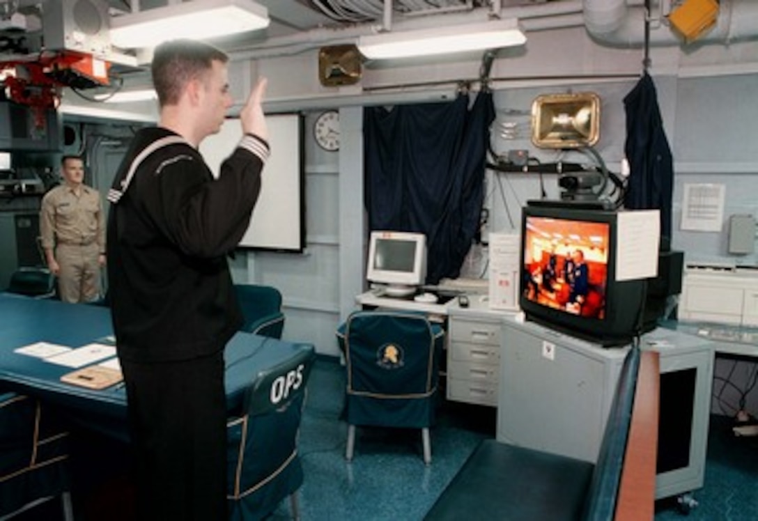 Petty Officer 2nd Class David Lee Jr. (left), from Virginia Beach, Va., is reenlisted aboard the aircraft carrier USS George Washington (CVN 73) by his father Capt. David Lee Sr., from Fairfax, Va., via video teleconferencing on Dec. 29, 1997. Capt. Lee conducted the ceremony from the Navy Command Center in the Pentagon as his son's ship steamed in the Persian Gulf. Washington and her embarked Carrier Air Wing One are operating in the Persian Gulf in support of Operation Southern Watch which is the U.S. and coalition enforcement of the no-fly-zone over Southern Iraq. 