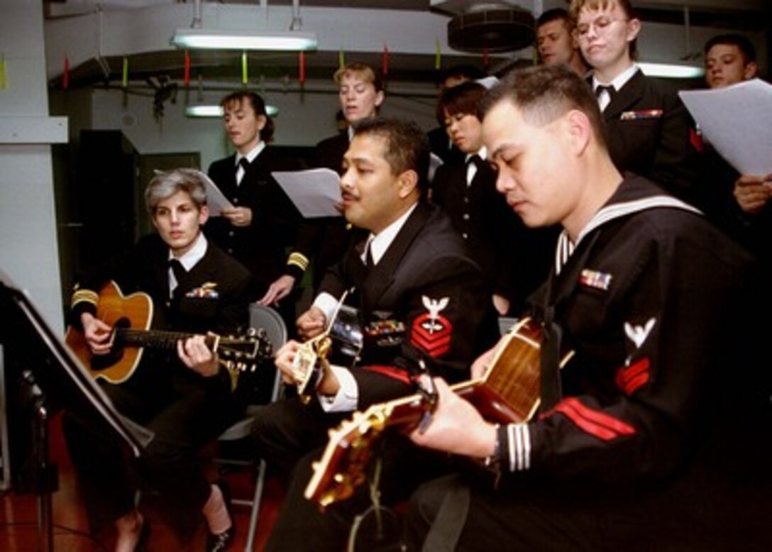 Petty Officer 2nd Class Feliciano Valencia (right) from Pampanga, Philippines, Chief Petty Officer Rene Abadesco (center) from Davao City, Philippines, and Lt. Cmdr. Donna Sengelaub (left) from Camp Springs, Md. provide musical accompaniment during the Roman Catholic midnight Mass aboard the aircraft carrier USS Nimitz (CVN 68) in the Persian Gulf on Dec. 25 1997. The Nimitz and embarked Carrier Air Wing 9 are operating in the Persian Gulf in support of Operation Southern Watch which is the U.S. and coalition enforcement of the no-fly-zone over Southern Iraq. 