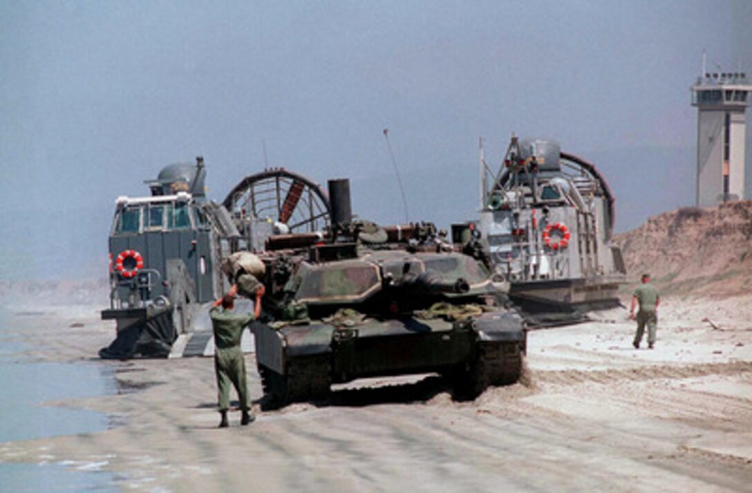 The driver of a U.S. Marine Corps M-1A1 Abrams tank is ground guided as he backs onto a U.S. Navy Landing Craft Air Cushion, or LCAC, as it sits on White Beach, Camp Pendleton, Calif., on June 20, 1997, during Exercise Kernel Blitz 97. Kernel Blitz 97 is a major amphibious exercise taking place in Southern California and waters offshore. More than 12,000 sailors, Marines, soldiers, guardsmen and airmen are involved in the exercise which is designed to test the Navy-Marine Corps team's ability to project combat power ashore. The LCAC, from Assault Craft Unit 5, will haul the tank, cargo and troops to the USS Comstock (LSD 45) operating offshore. 
