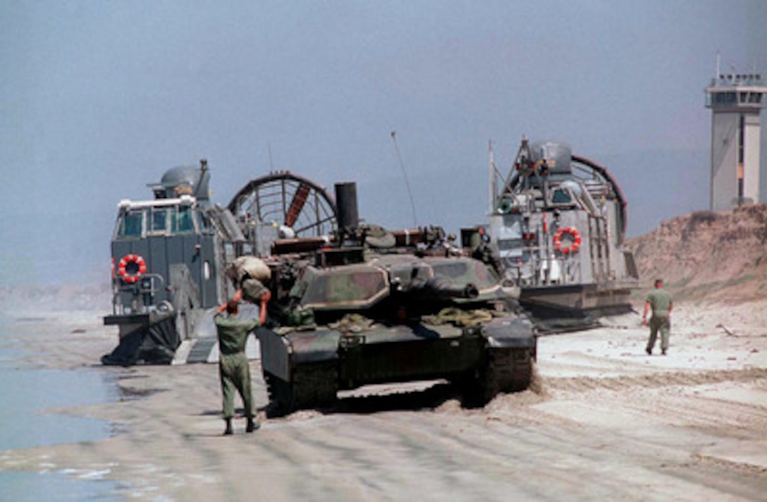The driver of a U.S. Marine Corps M-1A1 Abrams tank is ground guided as he backs onto a U.S. Navy Landing Craft Air Cushion, or LCAC, as it sits on White Beach, Camp Pendleton, Calif., on June 20, 1997, during Exercise Kernel Blitz 97. Kernel Blitz 97 is a major amphibious exercise taking place in Southern California and waters offshore. More than 12,000 sailors, Marines, soldiers, guardsmen and airmen are involved in the exercise which is designed to test the Navy-Marine Corps team's ability to project combat power ashore. The LCAC, from Assault Craft Unit 5, will haul the tank, cargo and troops to the USS Comstock (LSD 45) operating offshore. 
