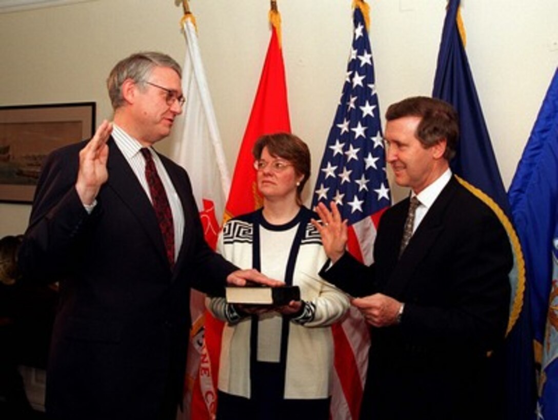Secretary of Defense William S. Cohen (right) administers the oath of office to Dr. John J. Hamre (left) as the twenty-sixth deputy secretary of Defense as Hamre's wife (center) holds the Bible in a Pentagon ceremony on July 29, 1997.   Hamre received Senate confirmation by unanimous consent on July 24.   Hamre most recently served as the under secretary of Defense (Comptroller), assuming those duties in October 1993. Before coming to the department, he served for ten years as a professional staff member of the Senate Armed Services Committee. In this capacity he was primarily responsible for the oversight and evaluation of procurement and research and development programs. From 1978 to 1984, he served in the Congressional Budget Office, rising to the position of deputy assistant director for National Security and International Affairs. Hamre received his doctorate with distinction from the School of Advanced International Studies at Johns Hopkins University. In 1972, he received his bachelor's degree from Augustana College, Sioux Falls, S.D., emphasizing political science and economics. The following year he studied as a Rockefeller Fellow at the Harvard Divinity School.  