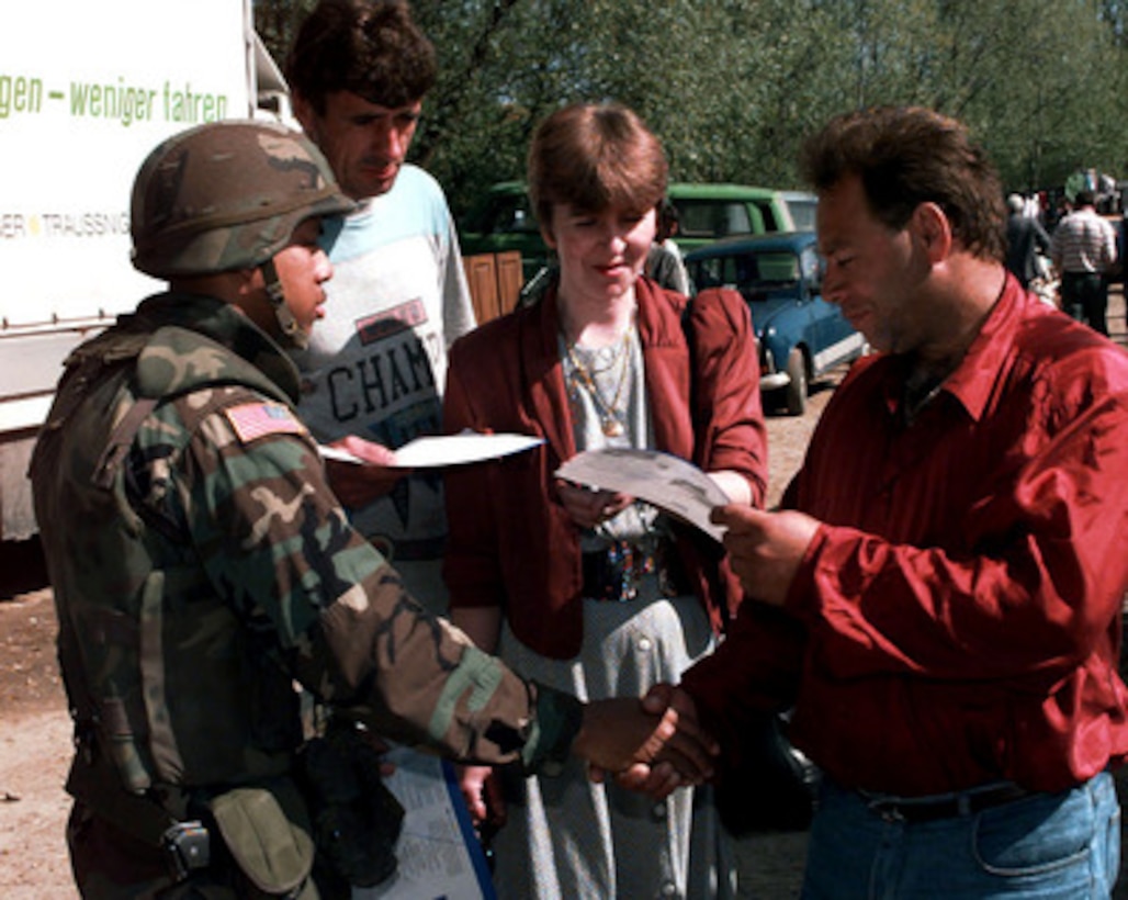 Sgt. Warren Lewis, U.S. Army, greets local Muslim shoppers as he hands out voter registration leaflets at the market place in Tojsici, Bosnia and Herzegovina, on May 10, 1997. Lewis is attached to the 312th Psychological Operations Company, Washington D.C. 