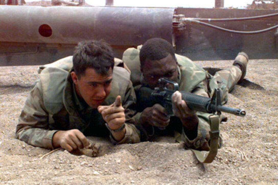 Cpl. L.H. Gastin (left) and Lance Cpl. D.K. Stallworth (right) provide perimeter security for the M-198 Howitzer during live-fire at the Marine Corps Air Ground Combat Center, Twentynine Palms, Calif., as part of Combined Arms Exercise 5-97, on April 11, 1997. The Marine Air Ground Task Force exercise is allowing these Marines of Golf Battery, 2nd Battalion, 10th Marines, to practice their desert warfare at the Twentynine Palms Lead Mountain Range. Gastin is from Utica, N.Y., while Stallworth is from Chicago, Ill. 