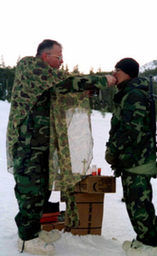 U.S. Navy Chaplain Thomas W. Falkenthal gives communion to a Marine during a Catholic mass held in the snow at Silver Creek, Calif., on Feb. 2, 1997. Marines from the 2nd Marine Regiment and 3rd Battalion, 8th Marines of Camp Lejeune, N. C. are at the Mountain Warfare Training Center, Bridgeport, Calif., to train in cold weather survival and arctic warfare. Cmdr. Falkenthal is the 2nd Marine Regiment chaplain. 