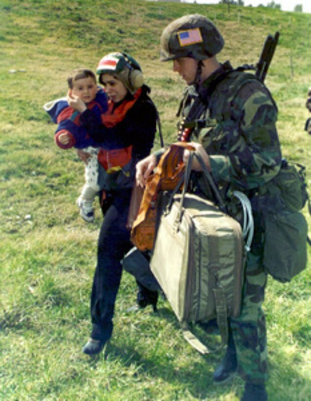 Military Policeman Sgt. David Smith, U.S. Marine Corps, escorts a woman and her child towards a waiting helicopter in a field inside the U.S. Embassy housing compound at Tirana, Albania, on March 14, 1997, during Operation Silver Wake. Marines from the 26th Marine Expeditionary Unit (Special Operations Capable) are performing a Non-combatant Evacuation Operation (NEO) to ensure the safety of American citizens and designated third country nationals. The Marines are part of the USS Nassau (LHA 4) Amphibious Readiness Group. 
