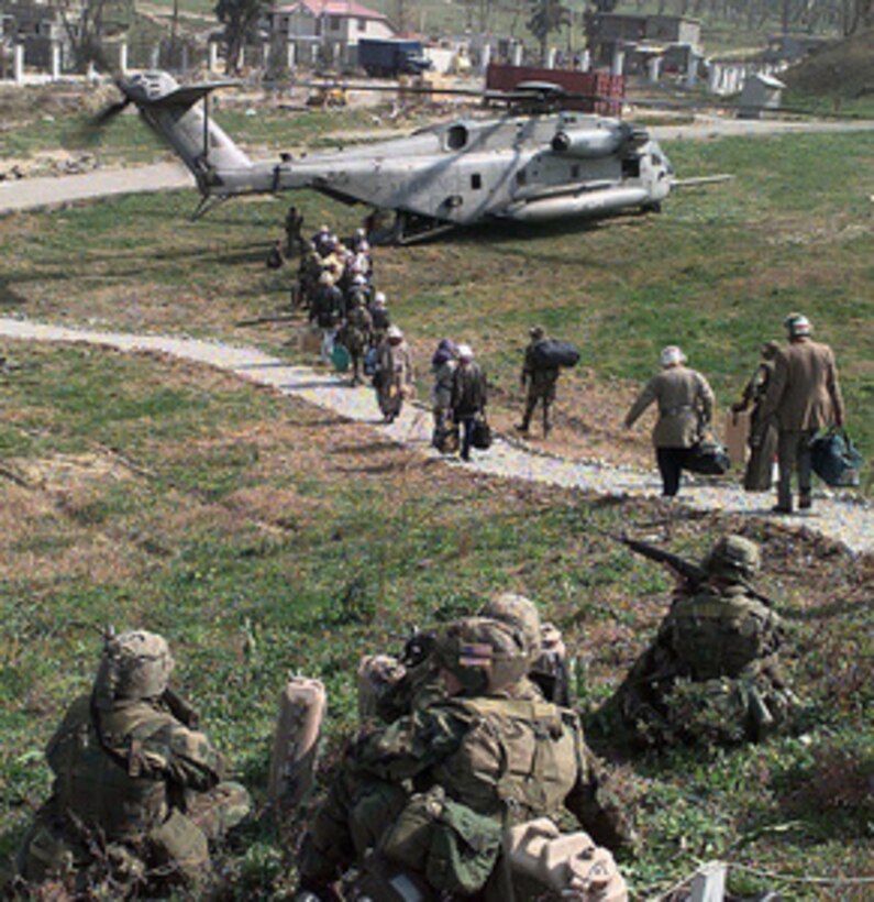 American citizens walk single-file through a heavily guarded perimeter to board a U.S. Marine Corps CH-53 Super Stallion combat assault helicopter in a field inside the U.S. Embassy housing compound in Tirana, Albania, on March 15, 1997. Operation Silver Wake is the evacuation of noncombatants from Albania to ensure the safety of American citizens and designated third country nationals. U.S. Naval forces from the USS Nassau (LHA 4) Amphibious Readiness Group continue to evacuate citizens from the U.S. Embassy in Tirana. 