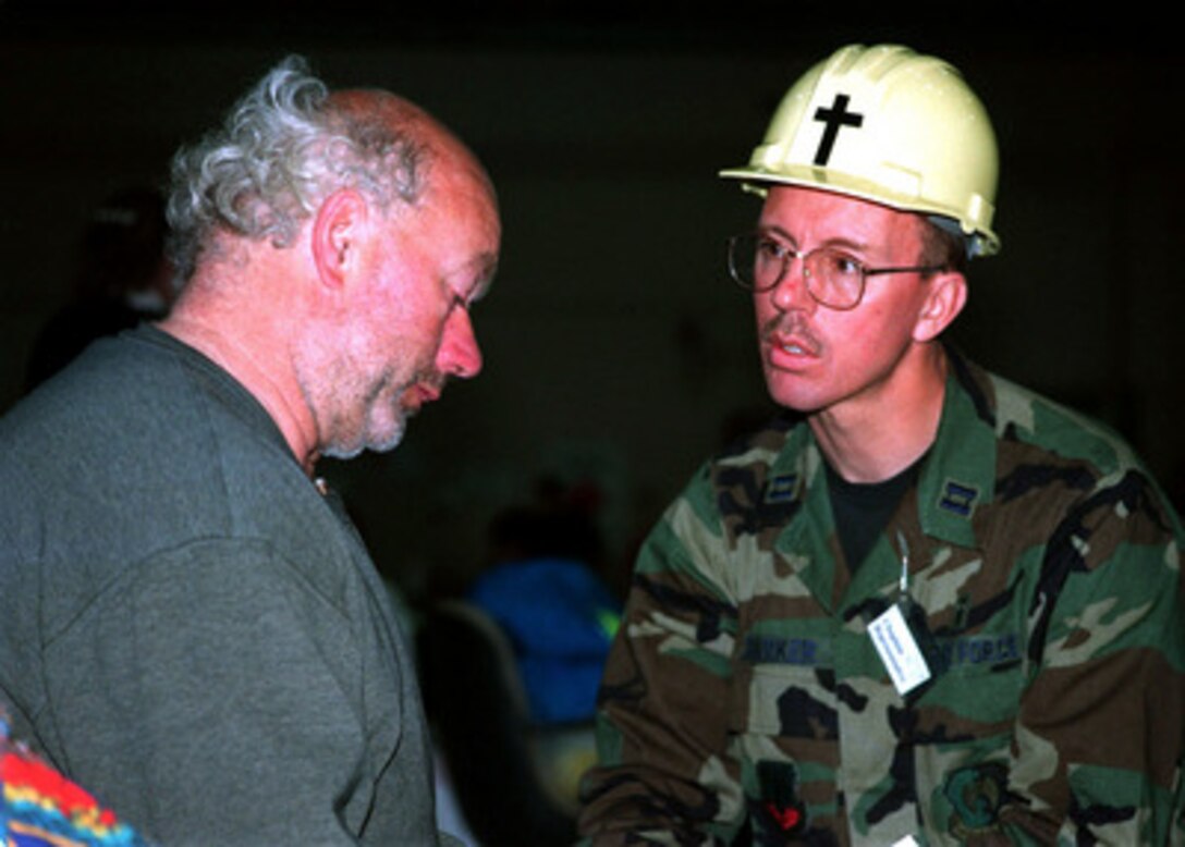 U.S. Air Force Chaplain Lonnie Barber (right) listens on April 24, 1997, as Elbert Grubert (left) tells him what he has lost in the flood. The hangars at Grand Forks Air Force Base, N.D., are being used as temporary shelter for thousands of Grand Forks residents who were displaced by the flood waters of the Red River. Barber is deployed for the relief efforts from Minot Air Force Base, N.D. 