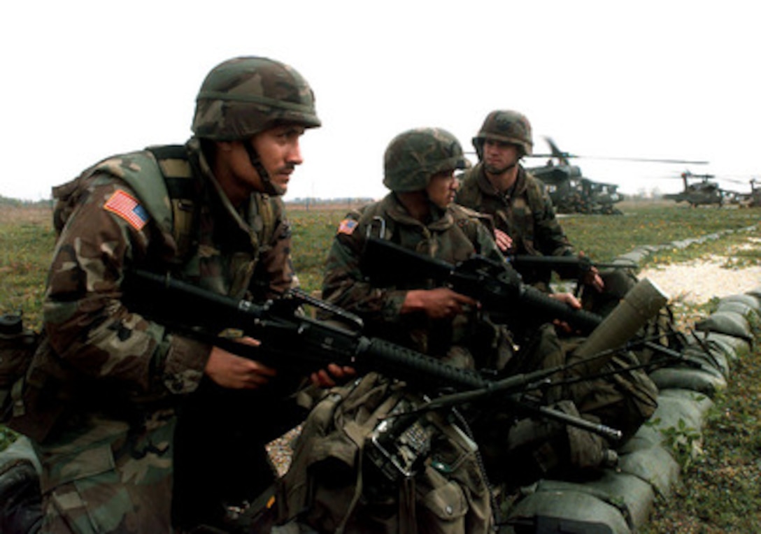 Three Charlie Company soldiers provide security while their fellow soldiers load into UH-60 Black Hawk helicopters during company air assault training at Camp McGovern, Bosnia and Herzegovina, on April 30, 1997. The soldiers will also learn about the mission of Task Force 1-77 at Camp McGovern, force protection, and setting up a temporary checkpoint as part of Operation Joint Guard. These soldiers are attached to the 2nd Battalion, 14th Infantry, 10th Mountain Division, Fort Drum, N.Y. 