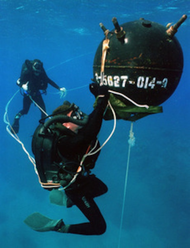 U.S. Navy diver David Ahearn attaches an inert satchel charge to a training mine, during training exercises in waters off Naval Base Guantanamo Bay, Cuba, on Feb. 15, 1997. Ahearn is a Aviation Ordnanceman 1st Class. 