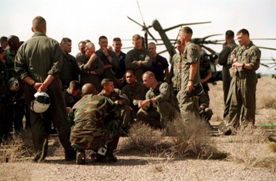 Pilots and aircrewman make the desert floor near Yuma, Ariz., their ready room as they gather together for a briefing during Exercise Desert Punch on April 17, 1997. Desert Punch is a simulated helicopter assault mission involving over 60 helicopters from nine squadrons of Marine Aircraft Group 16. The helicopters launched from Marine Corps Air Stations El Toro and Tustin, Calif., and rendezvoused at the designated landing zone outside Yuma. 
