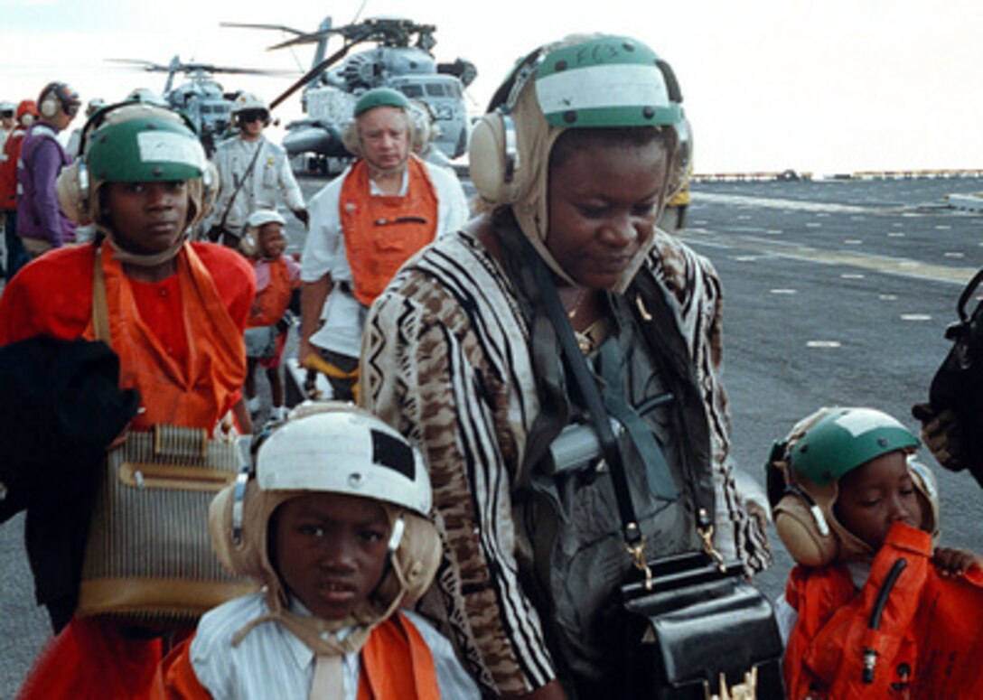 Evacuees from Freetown, Sierra Leone, are escorted across the flight deck of the USS Kearsarge (LHD 3), on May 30, 1997, during Operation Noble Obelisk. Over 900 people from 40 different countries have been evacuated. 