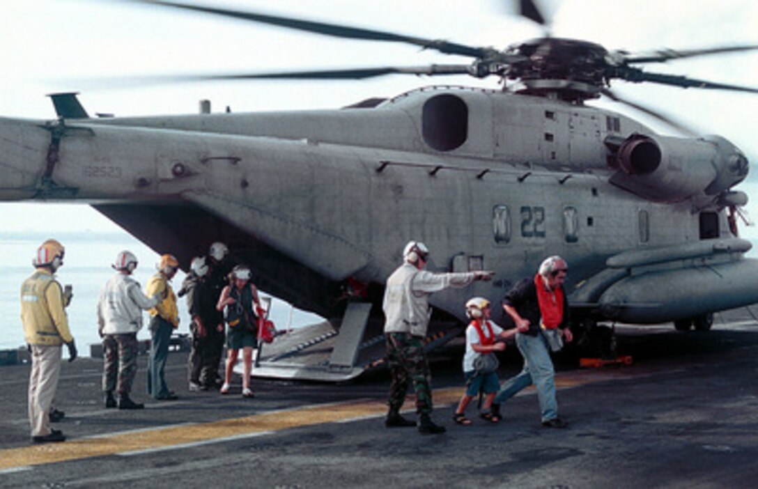 Evacuees from Freetown, Sierra Leone, are directed from a CH-53 Sea Stallion helicopter across the flight deck of the USS Kearsarge (LHD 3), on May 30, 1997, during Operation Noble Obelisk. Over 900 people from 40 different countries have been evacuated. 