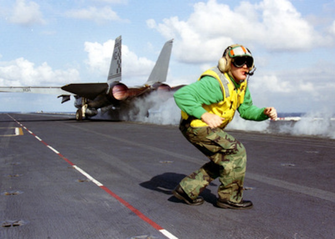 As an F-14 Tomcat roars down one of the four steam driven catapults of the aircraft carrier USS Nimitz (CVN 68) Petty Officer 1st Class John Macaby moves quickly to ready the next aircraft for launch during flight operations in the Persian Gulf on Nov. 4, 1997. The Nimitz and embarked Carrier Air Wing 9 are operating in the Persian Gulf in support of the U.S. and coalition enforcement of the no-fly-zone over Southern Iraq. Macaby, from Kent, Wash., is a Navy aviation boatswain's mate (equipment). 