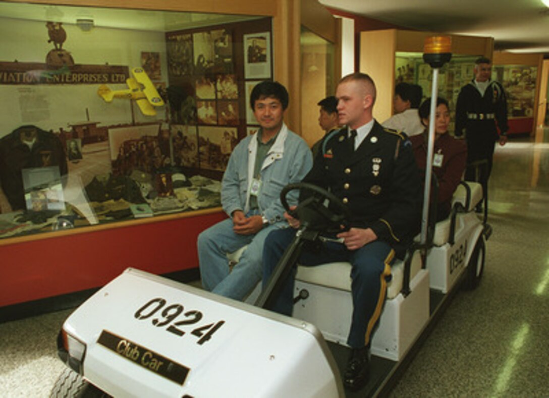 Mr. Jianyi Yang of Sichuan, China, an employee of the Consulate General of the People's Republic of China, in San Francisco, California, was honored at the Pentagon, October 22, 1997, as the 130,861st visitor of the year, breaking the old record set in 1996. Army specialist Ron Gore, a Pentagon tour guide, assisted by Petty Officer Signalman 3d Class John Albano (standing to the rear), conducted the tour for Mr. Yang and his three guests - all from Beijing, China. In addition to the special motorized tour of the world's largest office building, Mr. Yang was presented a certificate and special medallions struck for Secretary of Defense William Cohen and the Pentagon tour guides. 