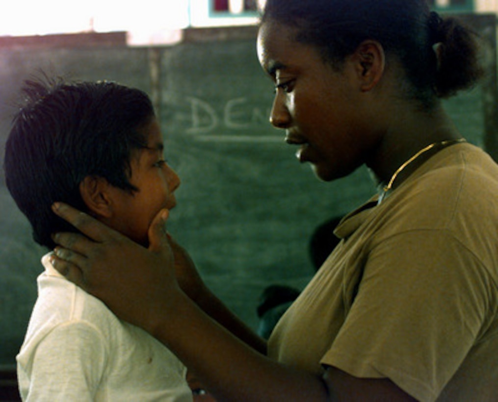 Sgt. Angela Williams examines a young patient's teeth while he waits to see the dentist during a medical civil assistance program in Guyana on Sept. 3, 1997. The program is part of the joint-combined humanitarian Exercise New Horizon Guyana 1997. U.S. forces, the Guyana Defense Force and local community leaders are working together to accomplish engineer construction and medical projects. Williams is a U.S. Army National Guard dental assistant. 