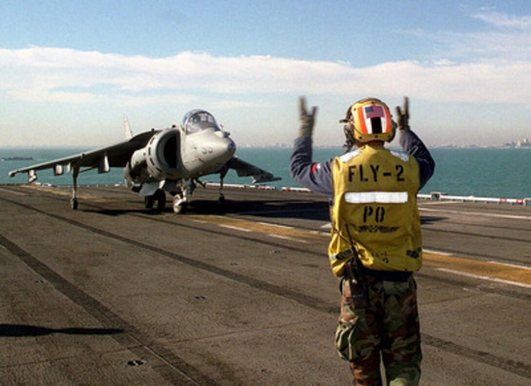 Petty Officer 2nd Class Mark Agurrie signals the pilot of an AV-8B Harrier to taxi aboard the amphibious assault ship USS Tarawa (LHA 1) as the ship operates off the coast of Kuwait City on March 23, 1998. Tarawa is deployed to the Persian Gulf in support of Operation Southern Watch, which is the U.S. and coalition enforcement of the no-fly-zone over Southern Iraq. Agurrie is a Navy aviation boatswain's mate. 