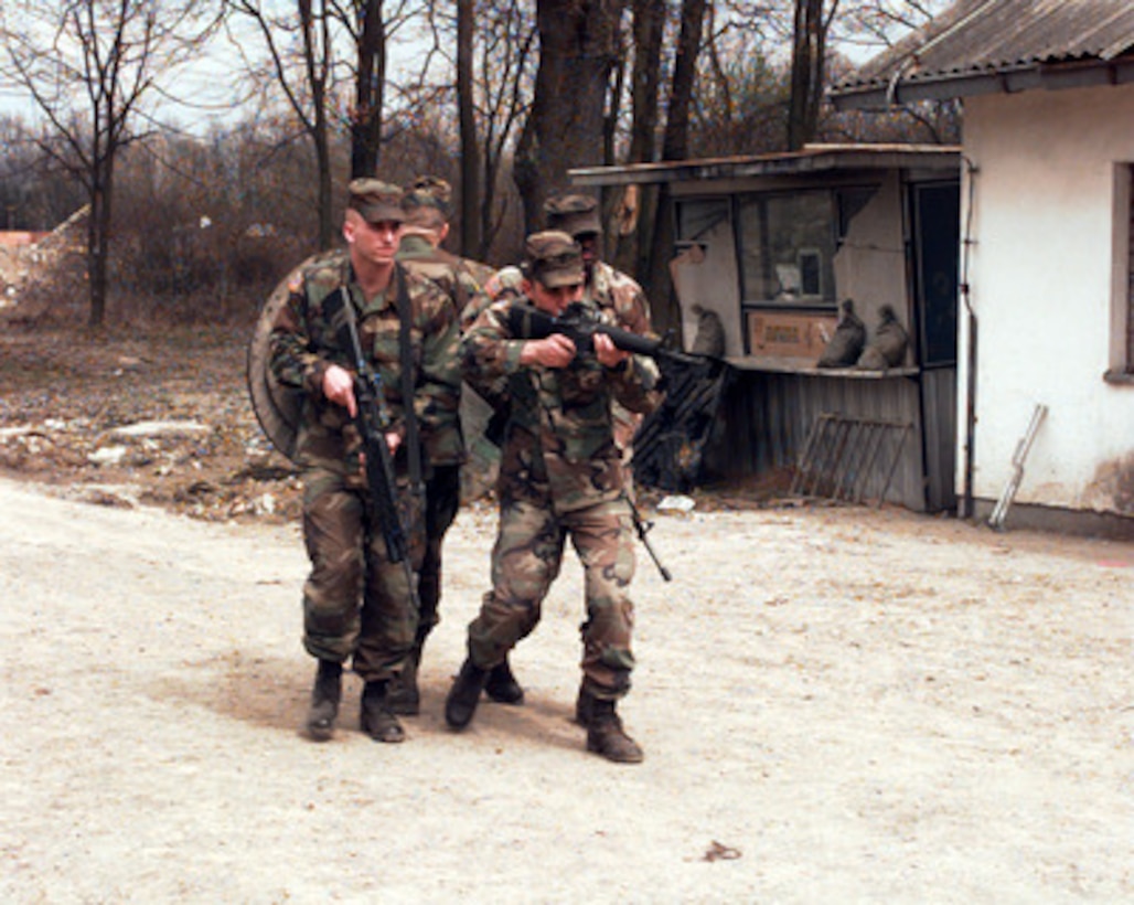 Spc. Adam Greene, Sgt. Erskine Foy, Spc. Nathan Cordova, and Spc. Jim Dennis practice a tight wedge formation as they maneuver at Eagle Base Tuzla, Bosnia and Herzegovina, on April 3, 1998. These U.S. Army soldiers, from Alpha Company, 2nd Battalion, 22nd Infantry Regiment, 10th Mountain Division, are deployed to Bosnia and Herzegovina as part of the Stabilization Force in Operation Joint Guard. 
