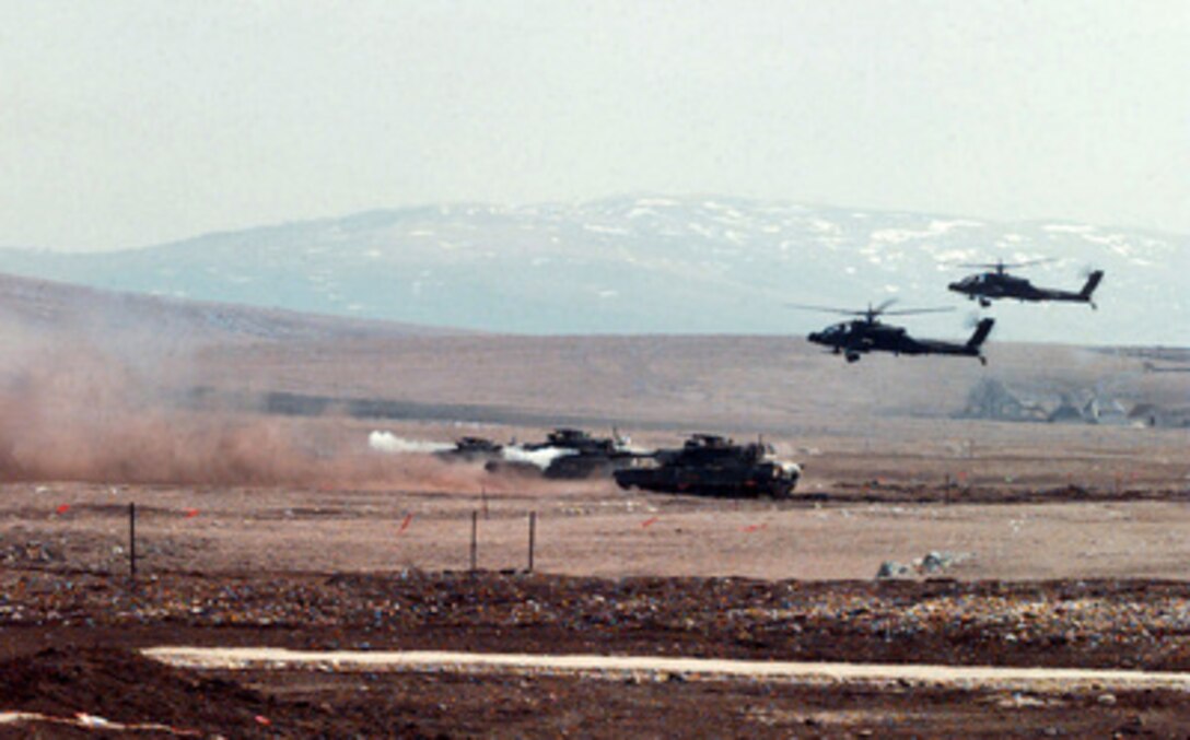 M1-A1 Abrams main battle tanks from the U.S. Army 1st Armored Division, along with two AH-64A Apache helicopters coordinate their fire as they practice at a range in Glamoc, Bosnia and Herzegovina, on April 2, 1998. The tankers and the helicopters are deployed to Bosnia and Herzegovina as part of the Stabilization Force in Operation Joint Guard. 