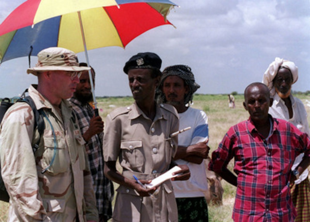 Capt. Moore (left), U.S. Army Civil Affairs, visits village leaders from the village of Madogashi, Kenya, after an air drop of corn by a U.S. Marine Corps C-130 Hercules outside the village on March 4, 1998. U.S. Central Command forces are conducting Operation Noble Response to provide disaster relief assistance to flood victims in Kenya. Central Command is working with the United States Agency for International Development and the World Food Program to deliver the aid which is being provided at the request of the government of Kenya. 
