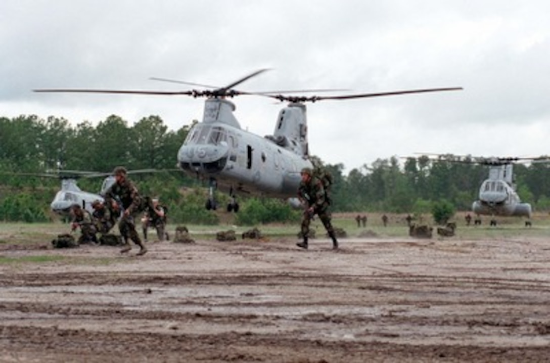 U.S. Marines from Bravo Company, 1st Battalion, 8th Marines, move away from CH-46 Sea Knight helicopters at Landing Zone Coot at Marine Corps Base Camp Lejeune, N.C., on April 22, 1998, during a rehearsal for Urban Warrior. Urban Warrior is a series of Limited Objective Experiments sponsored by the Marine Corps Warfighting Lab. The experimentation will examine the urban tactics of thrust and penetration, the use of man-portable shields and breaching technologies, and new tactical possibilities for hospital corpsmen. 