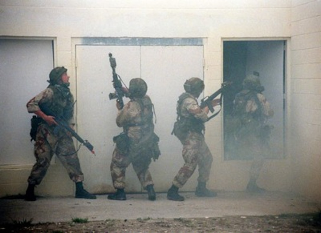Marines are nearly obscured by smoke as they maneuver their way through the Military Operations in Urban Terrain facility at Marine Corps Base Camp Lejeune, N.C., on April 22, 1998, during a rehearsal for Urban Warrior. Urban Warrior is a series of Limited Objective Experiments sponsored by the Marine Corps Warfighting Lab. The experimentation will examine the urban tactics of thrust and penetration, the use of man-portable shields and breaching technologies, and new tactical possibilities for hospital corpsmen. These Marines are attached to Bravo Company, 1st Battalion, 8th Marines. 