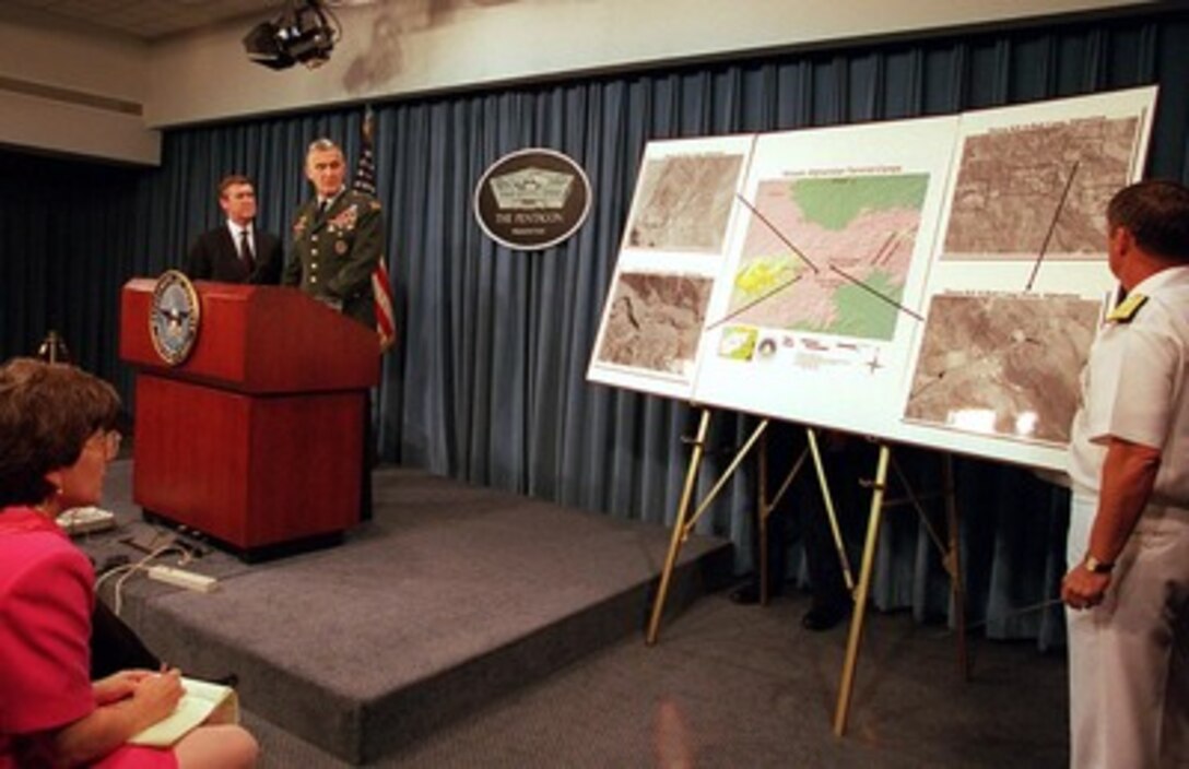 Secretary of Defense William S. Cohen (left) listens as Gen. Henry H. Shelton (right), U.S. Army, chairman, Joint Chiefs of Staff, briefs reporters in the Pentagon on the U.S. military strike on a chemical weapons plant in Sudan and terrorist training camps in Afghanistan on Aug. 20, 1998. 