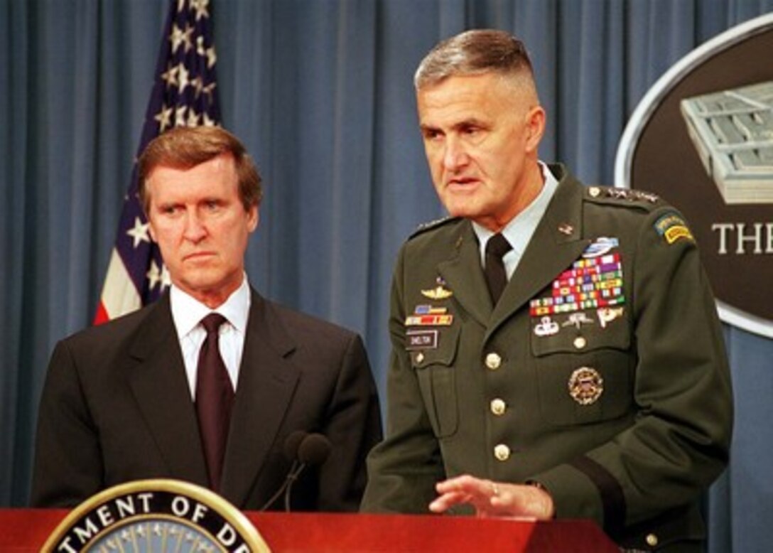 Secretary of Defense William S. Cohen (left) listens as Gen. Henry H. Shelton (right), U.S. Army, chairman, Joint Chiefs of Staff, briefs reporters in the Pentagon on the U.S. military strike on a chemical weapons plant in Sudan and terrorist training camps in Afghanistan on Aug. 20, 1998. 