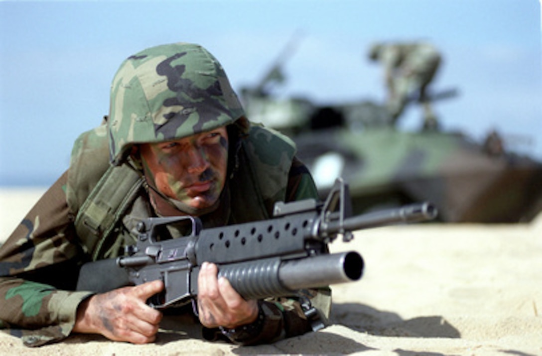 U.S. Marine Cpl. Scott Hobak forms part of a perimeter set up to protect Exercise RIMPAC '98 forces landing on the beach behind him during an amphibious assault at Barking Sands, Kauai, on July 31, 1998. RIMPAC '98 is a multinational exercise held on and in waters surrounding the Hawaiian islands, involving more than 25,000 people, 50 ships and 200 aircraft from Australia, Canada, Chile, Japan, the Republic of Korea, and the U.S. Hobak is from Atlanta Ga. 