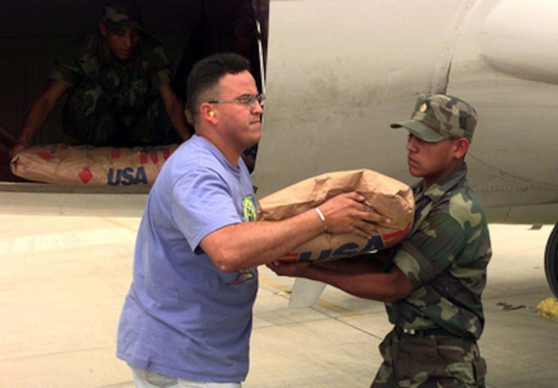 U.S. Air Force Staff Sgt. George T. Aguilar hands a 55-pound bag of rice to a Honduran airman as they unload a plane full of relief supplies at Soto Cano Air Base, Honduras, on Nov. 9, 1998. Over 1,000 U.S. service members are helping to rush food, shelter, pure water, medical aid and other relief supplies to the central Americans made homeless by Hurricane Mitch. Soto Cano is an intermediate staging base for the operation. From there the supplies are transported by trucks and smaller aircraft to distribution areas around the country. Aguilar is deployed from Detachment 1, 24th Wing, Howard Air Base, Panama. 
