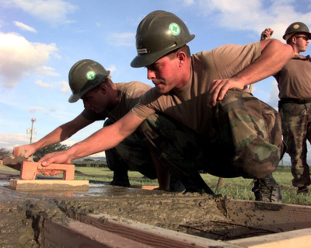 Seabees of Naval Mobile Construction Battalion 7 trowel cement as they pour flooring for a 500-person tent city for relief workers at Soto Cano Air Base, Honduras, on Nov. 10, 1998. Over 1,000 U.S. service members are helping to rush food, shelter, pure water, medical aid and other relief supplies to the central Americans made homeless by Hurricane Mitch. The Seabees are deployed from Roosevelt Roads, Puerto Rico and Gulfport, Miss. 