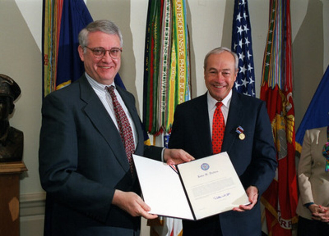 Deputy Secretary of Defense John J. Hamre (left) and Secretary of the Navy John H. Dalton (right) hold the citation for the Department of Defense Medal for Distinguished Public Service as they pose for photographers in the Pentagon on Nov. 13, 1998. Hamre presented the out-going Navy secretary the medal during a ceremony held in his honor. 