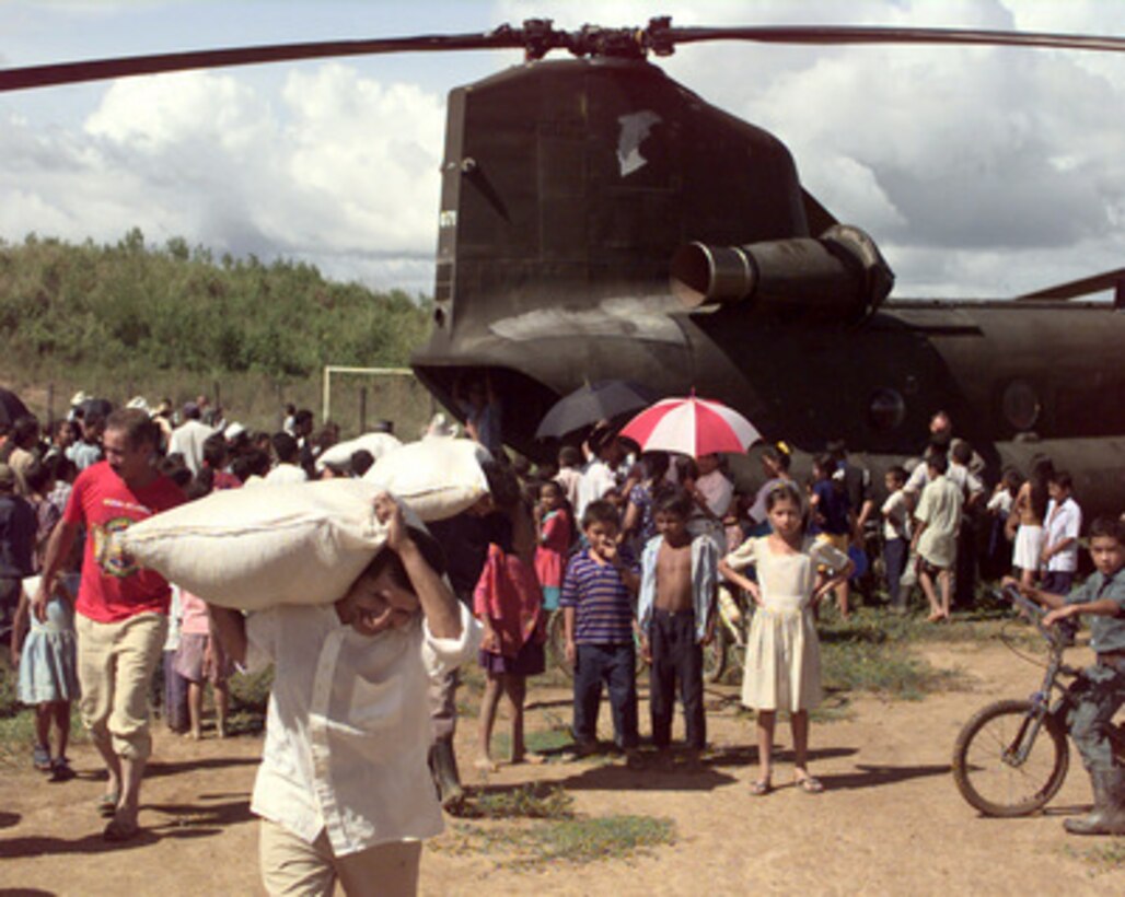 A man from the village of Casamacoa, Honduras, carries a sack of corn away from a U.S. Army CH-47 Chinook helicopter on Nov. 20, 1998. The helicopter, from the 159th Aviation Regiment, 18th Aviation Brigade, Fort Bragg, N.C., carried 11,000 pounds of food and clothing to the village. Over 1,800 U.S. service members are helping to rush food, shelter, pure water and medical aid to the central Americans made homeless by Hurricane Mitch. 