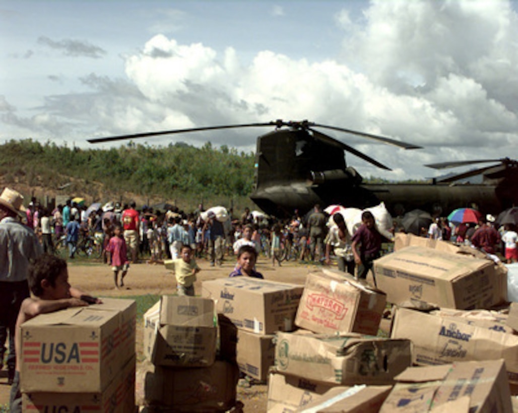 Villagers from Casamacoa, Honduras, carry relief supplies away from a U.S. Army CH-47 Chinook helicopter on Nov. 20, 1998. The helicopter, from the 159th Aviation Regiment, 18th Aviation Brigade, Fort Bragg, N.C., carried 11,000 pounds of food and clothing to the village. Over 1,800 U.S. service members are helping to rush food, shelter, pure water and medical aid to the central Americans made homeless by Hurricane Mitch. 