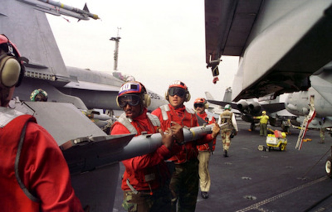 Aviation ordnancemen from Fighter Squadron 32 use teamwork and brute strength to load an AIM-9M Sidewinder missile onto an F-14 Tomcat on the flight deck of the USS Enterprise (CVN 65) as the aircraft carrier operates in the Persian Gulf on Dec. 1, 1998. Enterprise and its embarked Carrier Air Wing 3 are on station in the Persian Gulf in support of Operation Southern Watch, which is the U.S. and coalition enforcement of the no-fly-zone over Southern Iraq. The Tomcat belongs to Fighter Squadron 32, Naval Air Station Oceana, Va. 