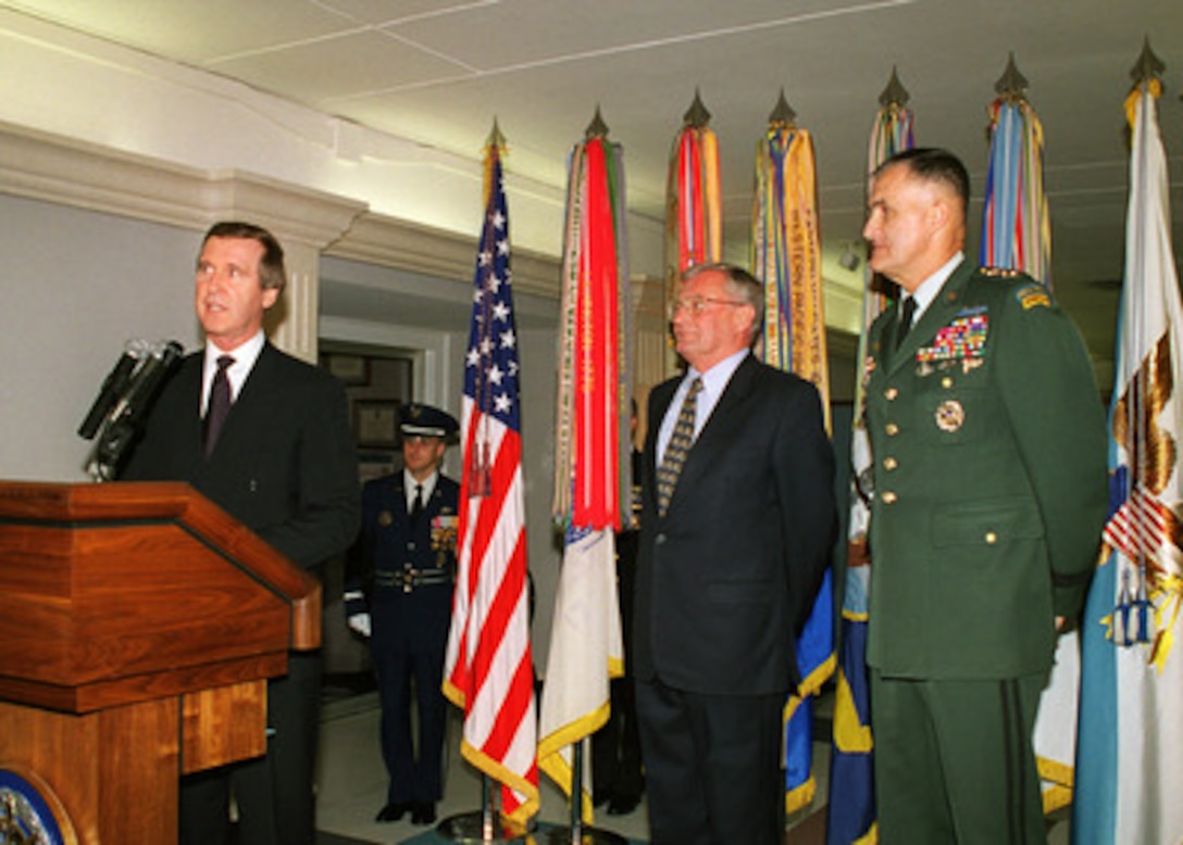 Secretary of Defense William S. Cohen (left) addresses the audience during a ceremony to honor retired Gen. John M. Shalikashvili (center), U.S. Army, at a ceremony in the Pentagon on Dec. 7, 1998. Cohen and present Chairman of the Joint Chiefs of Staff Gen. Henry H. Shelton (right), U.S. Army, are honoring the former chairman at an unveiling ceremony of a panel depicting his career in the military and his rise to become the 13th chairman of the Joint Chiefs of Staff. 