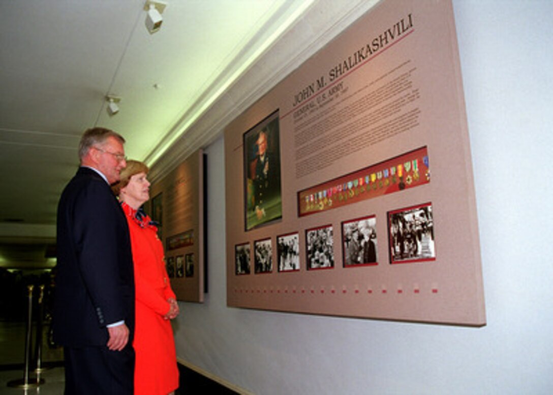 Retired Gen. John M. Shalikashvili, U.S. Army, and his wife Joan look at a panel depicting his career in the military and his rise to become the 13th chairman of the Joint Chiefs of Staff after the unveiling ceremony in the Pentagon on Dec. 7, 1998. Former chairmen retired Adm. Thomas H. Moorer, U.S. Navy, retired Gen. David C. Jones, U.S. Air Force, retired Gen. Colin L. Powell, U.S. Army, present Chairman of the Joint Chiefs of Staff Gen. Henry H. Shelton, U.S. Army, and Secretary of Defense William S. Cohen are gathered to honor Shalikashvili. 