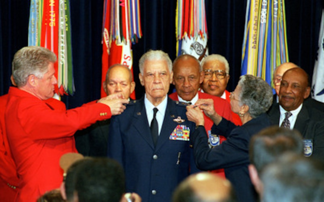 Wearing the trademark red blazer of the Tuskegee Airmen, President Bill Clinton (left) and Elnora Davis McLendon (right) pin the fourth star on the epaulets of retired U.S. Air Force Gen. Benjamin O. Davis in a White House ceremony on Dec. 9, 1998. Davis commanded the famed Tuskegee Airmen during World War II. Officially the 99th Pursuit Squadron and later, the 332nd Fighter Group, the Tuskegee Airmen were all black aircrews trained in Tuskegee, Ala. Flying in their red-tailed P-51 Mustang fighters, Davis and his men never lost a bomber to the enemy in hundreds of escort missions over Europe. McLendon is the sister of Davis. 
