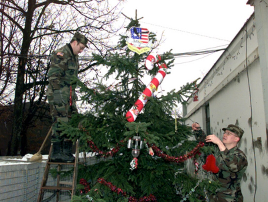 Staff Sgts. Alan Brunke (left), and Bryan Purtell (right) decorate a Christmas tree for the 401st Expeditionary Air Base Group at Tuzla Air Base, Bosnia and Herzegovina, on Dec. 15, 1998. Both are deployed to Tuzla in support of Operation Joint Forge. Brunke is deployed from F.E. Warren Air Force Base, Wyo. Purtell is deployed from Spangdahlem Air Base, Germany. 