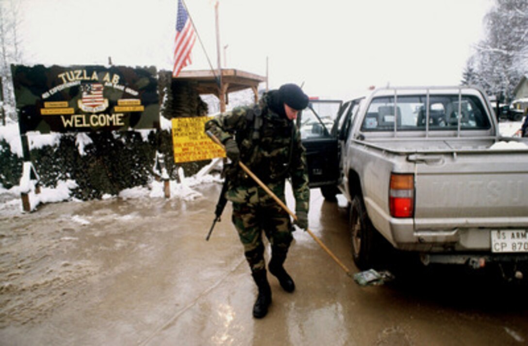 U.S. Air Force Security Policeman Airman 1st Class Marco C. Kalkbrenner uses a mirror on a pole to inspect the undercarriage of a vehicle before letting it enter Tuzla Air Base in Bosnia and Herzegovina, on Dec. 17, 1997. Kalkbrenner, from Virginia Beach, Va., is deployed to Tuzla from the 48th Security Forces Squadron out of RAF Lakenheath, United Kingdom, in support of Operation Joint Guard. He is attached to the 401st Expeditionary Air Base Group at Tuzla. 