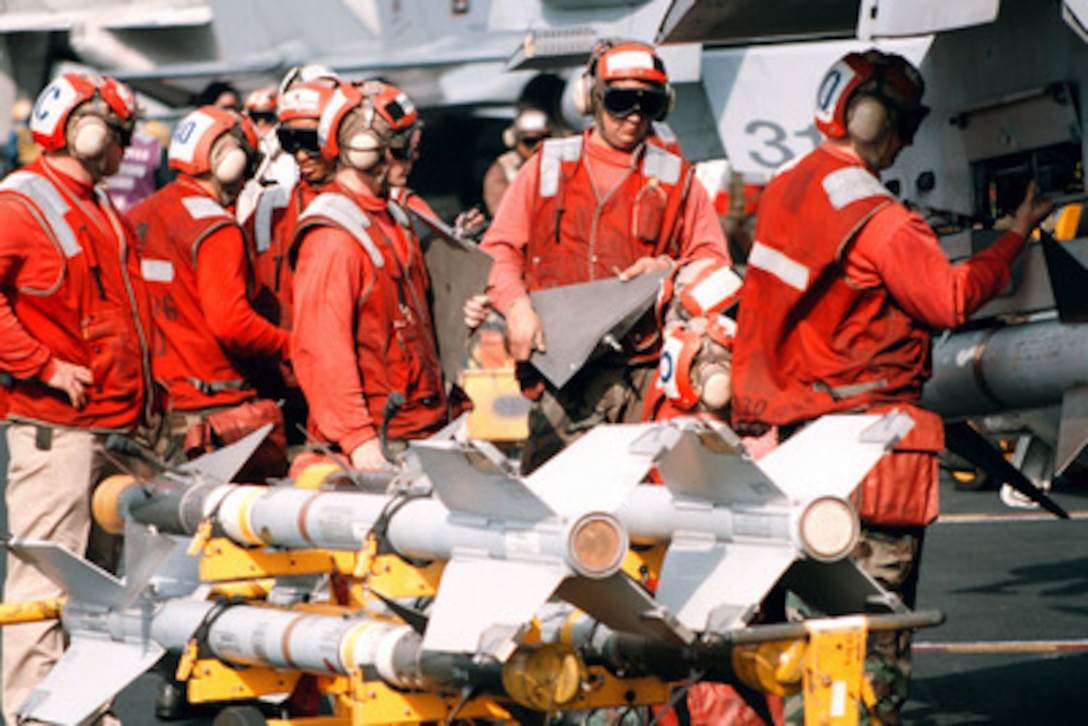 Red-shirted aviation ordnancemen from Marine Fighter Attack Squadron 251 load missiles onto an F/A-18C Hornet on the flight deck of the aircraft carrier USS George Washington (CVN 73) as the ship steams in the Persian Gulf on Jan. 2, 1998. The Washington battle group is operating in the Persian Gulf in support of Operation Southern Watch which is the U.S. and coalition enforcement of the no-fly-zone over Southern Iraq. Marine Fighter Attack Squadron 251 is deployed to the Washington from Marine Corps Air Station Beaufort. S.C. 