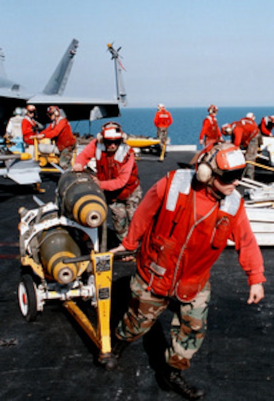 Aviation Ordnancemen David Dinardi (right), and William Bailey (left) transport MK-83 1,000 pound bombs across the flight deck of USS George Washington (CVN 73) as the ship steams in the Persian Gulf on Feb. 6, 1998. The Washington battle group is operating in the Persian Gulf in support of Operation Southern Watch which is the U.S. and coalition enforcement of the no-fly-zone over Southern Iraq. Dinardi is from Philadelphia, Pa. Bailey is from Louisburg, N.C. 