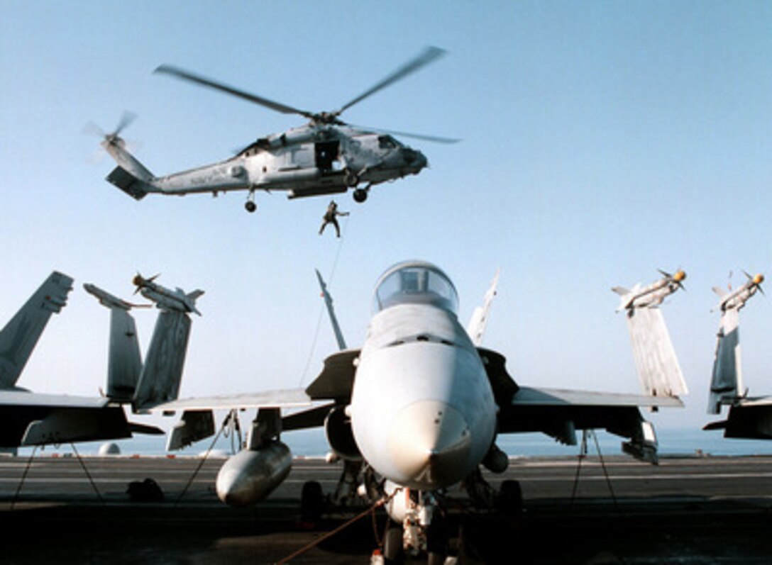 Members of the Explosive Ordnance Disposal team practice for a rapid insertion as they rappel from an SH-60B Seahawk helicopter to the flight deck of USS George Washington (CVN 73) as the ship steams in the Persian Gulf on Feb. 6, 1998. The Washington battle group is operating in the Persian Gulf in support of Operation Southern Watch which is the U.S. and coalition enforcement of the no-fly-zone over Southern Iraq. 