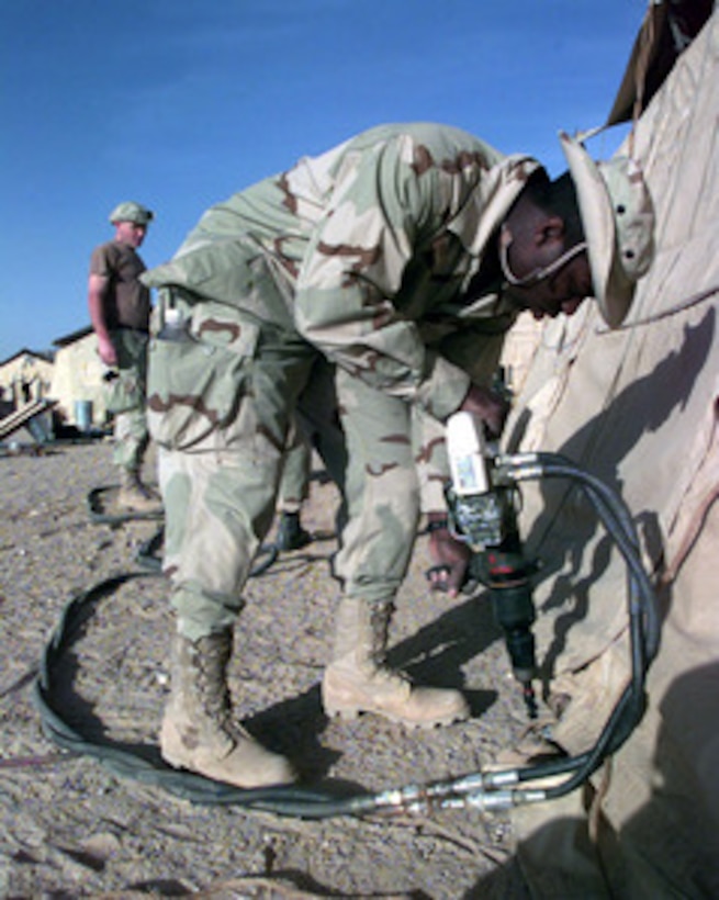 Senior Airman Jesse Hall uses an air-powered drill to bore a hole in the desert floor as he helps to erect a tent at an operating base in Southwest Asia on Feb. 17, 1998. Hall is one of over 400 U.S. Air Force personnel currently deployed to the Gulf region as part of an Air Mobility Command Tanker Task Force operating in the Southwest Asia theater in support of Operation Southern Watch. Southern Watch is the U.S. and coalition enforcement of the no-fly-zone over Southern Iraq. Hall is a transportation specialist from the 305th Transportation Squadron, McGuire Air Force Base, N.J. 