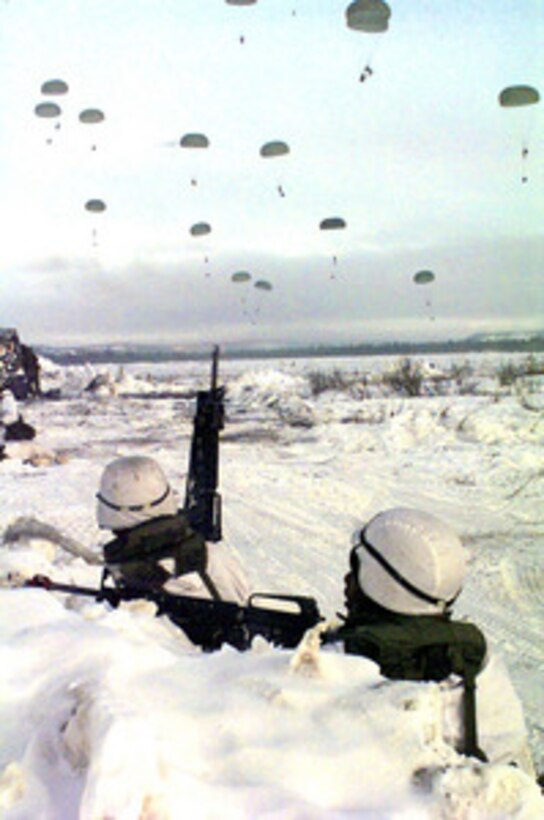 Two soldiers from the 1st Battalion, 501st Infantry (Airborne) take up defensive positions as the rest of their unit lands at the Donnely drop zone in Alaska on Feb. 18, 1998, during Exercise Northern Edge 98. More than 90,000 soldiers, sailors, Marines, airmen Coast Guardsmen and National Guardsmen are participating the exercise. Northern Edge 98 is designed to practice joint operational techniques and procedures, increasing interoperability between the services. 
