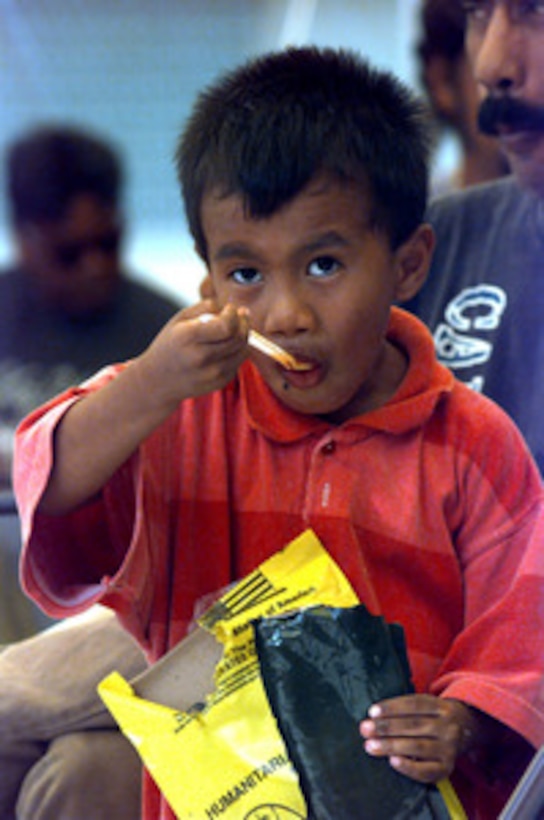 A little boy has a Humanitarian Meal Ready to Eat for a late lunch on Dec. 31, 1997, as his family waits for a room assignment at Andersen Air Force Base, Guam. The Air Force is converting some dormitories into temporary housing for people displaced by Super Typhoon Paka. The typhoon hit the island the evening of Dec. 16 with sustained winds of 175 mph. One wind gust recorded at Andersen was the strongest ever recorded on earth at 236 mph. 