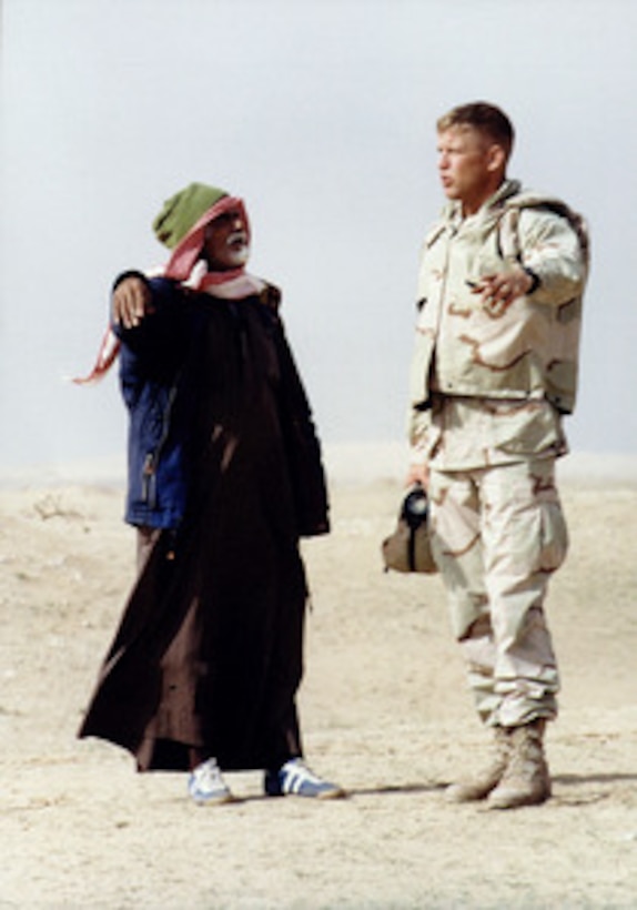 Sgt. Billy Montgomery, U.S. Marine Corps, converses with a Bedouin shepherd in Arabic on one of his daily range sweeps in Kuwait on Dec. 15, 1997. Montgomery and other Marines of the 13th Marine Expeditionary Unit are participating in Exercise Eager Mace 98. Eager Mace 98 is a joint, combined, amphibious, ground, air, and naval training exercise with U.S. and Kuwaiti armed forces. Montgomery uses his skills as a Marine interrogator/ translator to alert local Kuwaitis of the training taking place during the exercise. 
