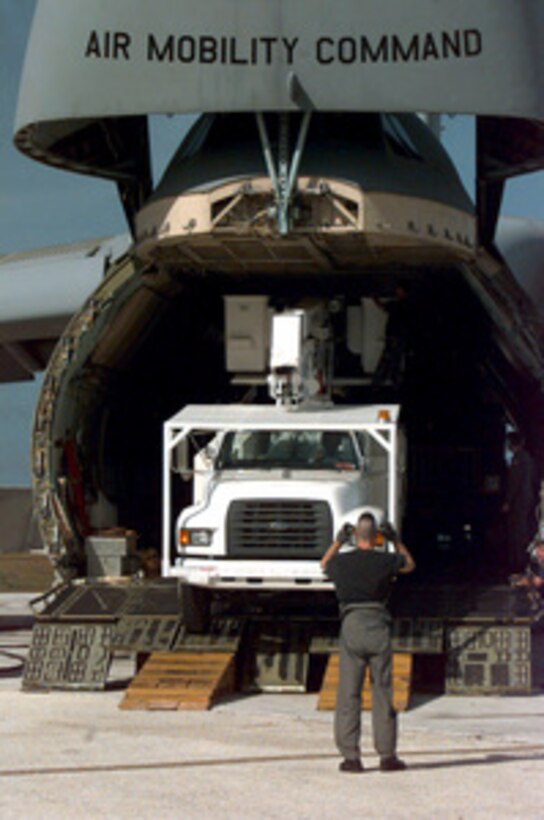 A U.S. Air Force airman directs the driver of a utility truck out of a C-5 Galaxy at Andersen Air Force Base, Guam, on Jan. 6, 1998. The Air Force is flying in utility trucks and other equipment to aid the Guam Power Authority in restoring power to the island after by Super Typhoon Paka. The typhoon hit the island the evening of Dec. 16 with sustained winds of 175 mph. One wind gust recorded at Andersen was the strongest ever recorded on earth at 236 mph. The Galaxy is deployed from Travis Air Force Base, Calif. 